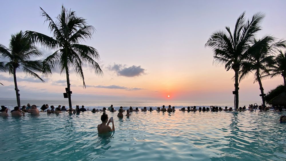 Piscine à débordement et cocotiers face à l'océan à Seminyak